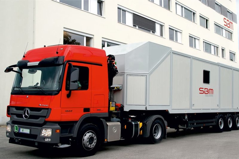 Service am fahrbaren Mischer von SBM Fahrbarer Mischer auf LKW-Anhänger vor Gebäude nach abgeschlossenem Service