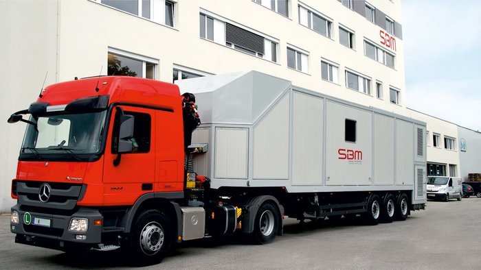 Service am fahrbaren Mischer von SBM Fahrbarer Mischer auf LKW-Anhänger vor Gebäude nach abgeschlossenem Service