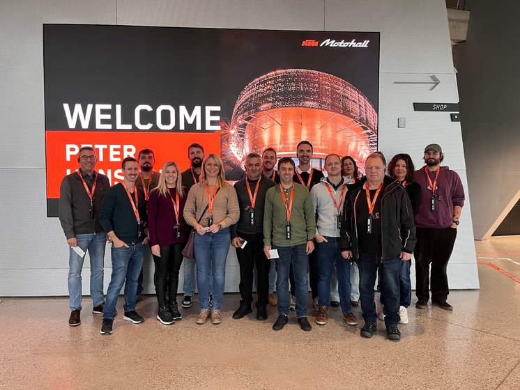 Willkommen bei KTM Motohall: Betriebsausflug 2024 Team Hasieber in der KTM Motohall vor einem Begrüßungsschild